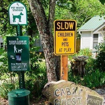 slow children and pets at play yellow sign, green and white pet waste station sign, green sign - please clean up after your dog